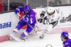Omaha Mavericks forward Ray Fust (8) battles for the puck against Niagara Purple Eagles defenseman Noah Carlin (5) in the first period during a college hockey match on Friday, October 13, 2023, in Omaha, Nebraska. Photo by John S. Peterson.