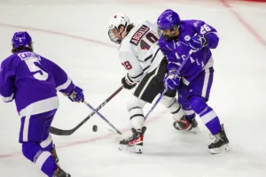 Omaha Mavericks forward Michael Abgrall (18) battles for the puck against Niagara Purple Eagles defenseman Alex Murray (26) in the second period during a college hockey match on Friday, October 13, 2023, in Omaha, Nebraska. Photo by John S. Peterson.