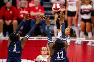 Nebraska Cornhusker Harper Murray (27) spikes the ball against Penn State Nittany Lions Taylor Trammell (1) and Zoe Weatherington (17) in the third set during a college volleyball match on Saturday, October 14, 2023, in Lincoln, Nebraska. Photo by John S. Peterson.