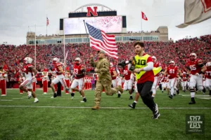 Former Husker offensive lineman Chris Long runs the flag out leading the team out on to the field before taking on the Maryland Terrapins on Saturday, November 11, 2023, in Lincoln, Nebraska. Photo by John S. Peterson.