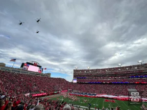 Three Army Guard CH-47 Chinook helicopters from Grand Island flyove as a football sized American flag unfurled for the National Anthem and Veteran's Day celebration before the football game between the Nebraska Cornhuskers and the Maryland Terrapins  on Saturday, November 11, 2023, in Lincoln, Nebraska. Photo by John S. Peterson.