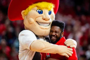 Nebraska Cornhusker mascot Herbie gives the MC D-Wayne a hug on the court at a break in the action against the South Carolina State Bulldogs during a college basketball game on Friday, December 29, 2023, in Lincoln, Nebraska. Photo by John S. Peterson.