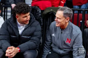 Nebraska Cornhuskers football commit Dylan Riaola and head volleyball coach John Cook sharing a conversation during a college basketball game against the Ohio State Buckeyes on Tuesday, January 23, 2024, in Lincoln, Nebraska. Photo by John S. Peterson.
