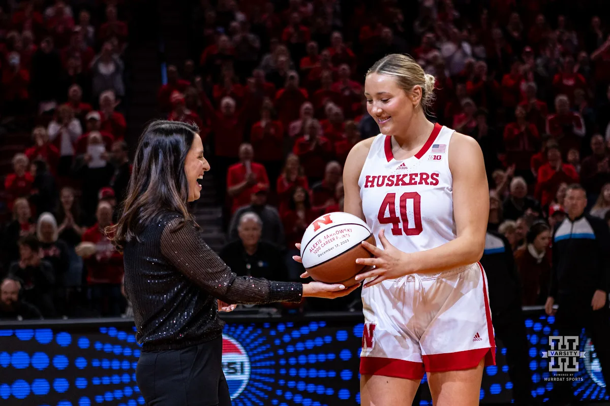 Nebraska Cornhusker head coach Amy Williams hands Alexis Markowski a basketball celebrating 1000 career points before the game against the Maryland Terrapins during a college basketball game on Sunday, December 31, 2023, in Lincoln, Nebraska. Photo by John S. Peterson.