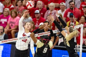 Nebraska Cornhusker Lindsay Krause (22) spikes the ball against Purdue Boilermaker middle blocker Lourdès Myers (9) and Kenna Wollard during a college volleyball match Friday, October 11, 2024, in Lincoln, Nebraska. Photo by John S. Peterson.