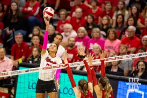 Nebraska Cornhusker Harper Murray (27) tips the ball over Rutgers Scarlet Knight middle blocker Natalie Robinson (9) and Aly Borellis during a college volleyball match Saturday, October 12, 2024, in Lincoln, Nebraska. Photo by John S. Peterson.