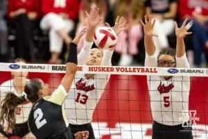 Nebraska Cornhusker Merritt Beason (13) and Rebekah Allick jump to block Purdue Boilermaker outside hitter Chloe Chicoine (2) during a college volleyball match Friday, October 11, 2024, in Lincoln, Nebraska. Photo by John S. Peterson.