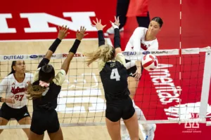 Nebraska Cornhusker Merritt Beason (13) spikes the ball against Purdue Boilermaker outside hitter Kenna Wollard (4) and Raven Colvin during a college volleyball match Friday, October 11, 2024, in Lincoln, Nebraska. Photo by John S. Peterson.